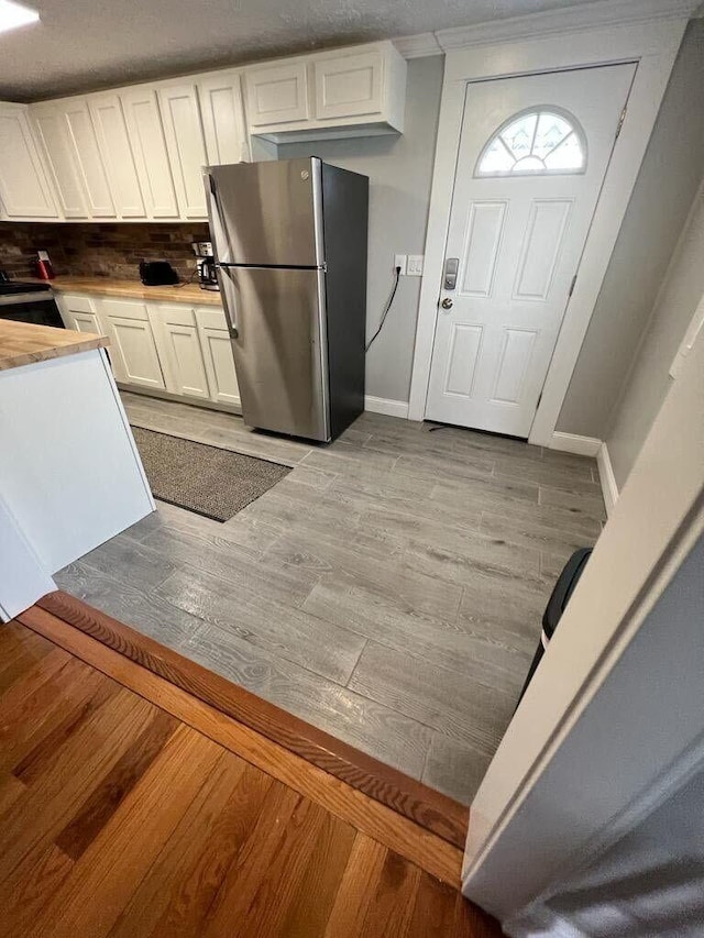 kitchen featuring freestanding refrigerator, baseboards, light wood-type flooring, light countertops, and white cabinetry