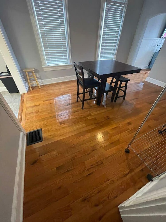 dining space with baseboards, hardwood / wood-style floors, and visible vents