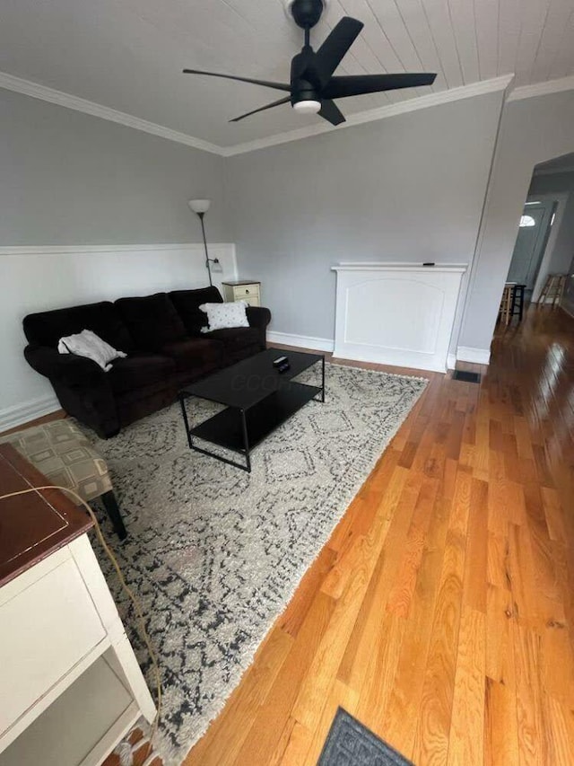 living room with baseboards, ceiling fan, ornamental molding, and hardwood / wood-style flooring