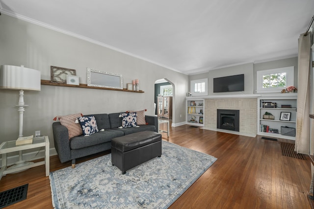 living room with arched walkways, ornamental molding, wood finished floors, and visible vents