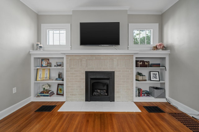 unfurnished living room featuring plenty of natural light, a brick fireplace, wood finished floors, and visible vents