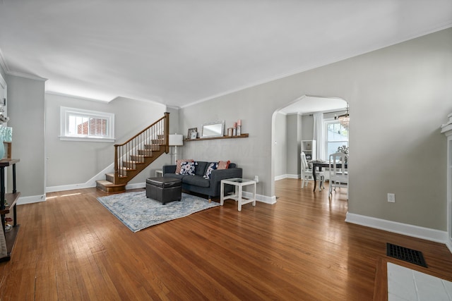 living room featuring baseboards, arched walkways, wood finished floors, and stairway