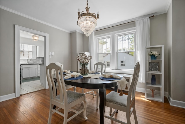 dining space featuring baseboards, ornamental molding, wood finished floors, and a chandelier