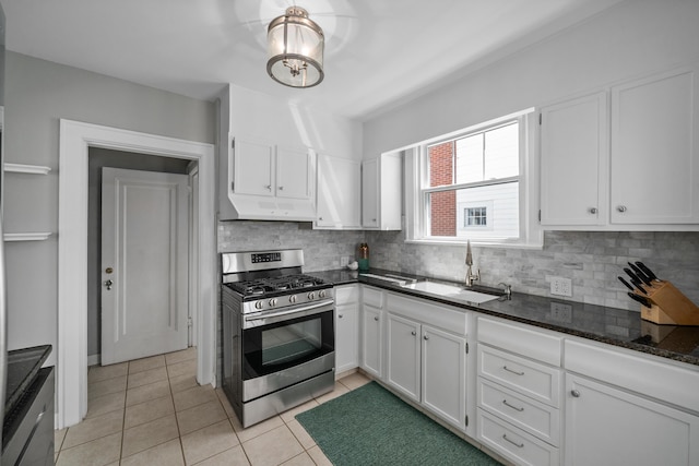 kitchen with backsplash, white cabinetry, a sink, and stainless steel gas range oven