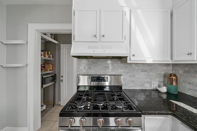 kitchen featuring under cabinet range hood, white cabinetry, backsplash, and gas range