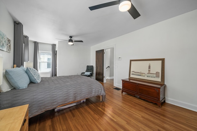 bedroom with a ceiling fan, baseboards, visible vents, and wood finished floors