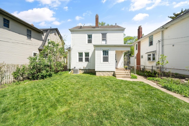 rear view of property featuring central air condition unit, a lawn, fence, and a chimney