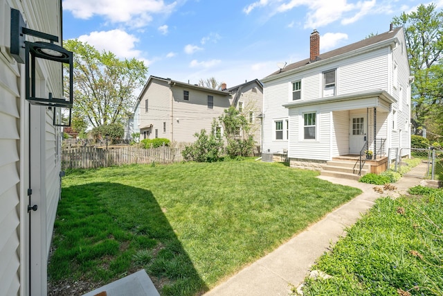 rear view of property featuring fence, a yard, and a chimney