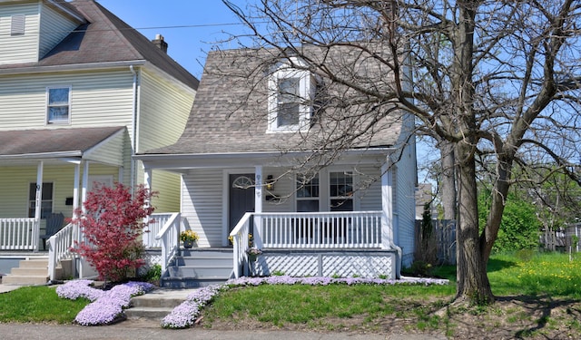 view of front facade with covered porch and a shingled roof