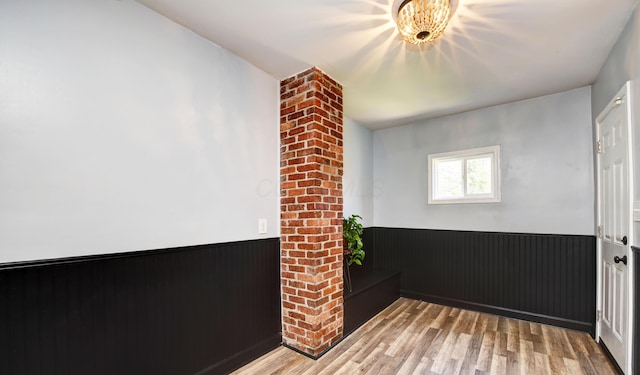 unfurnished room featuring light wood-style floors, wainscoting, and wood walls