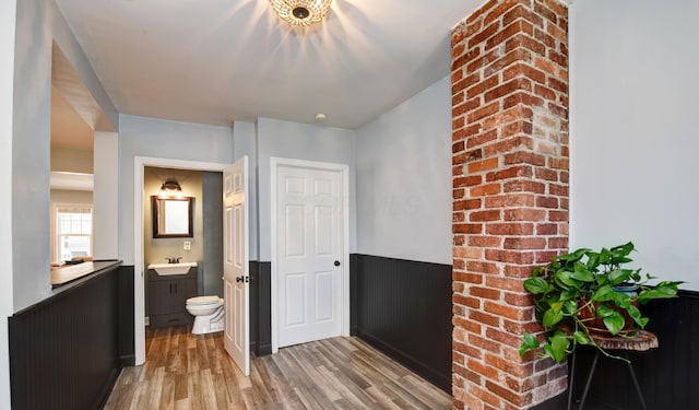 hallway featuring wainscoting, a sink, and light wood-style floors