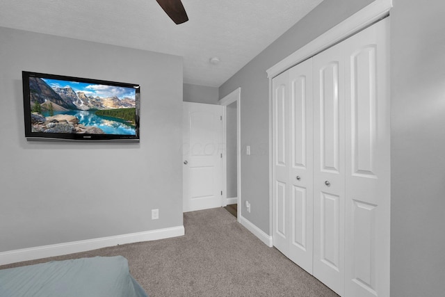 unfurnished bedroom featuring a closet, baseboards, a textured ceiling, a ceiling fan, and carpet