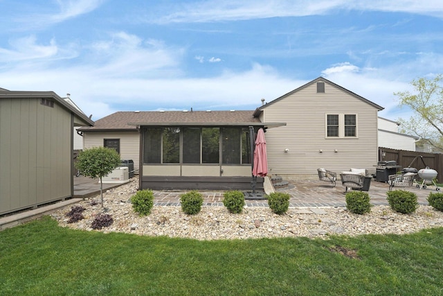 back of house featuring a sunroom, roof with shingles, a patio area, and a lawn