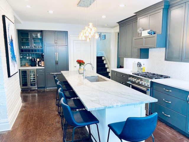 kitchen with beverage cooler, a sink, stainless steel stove, and tasteful backsplash