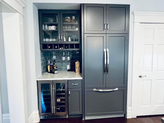bar with wine cooler, dark wood-style floors, built in fridge, tasteful backsplash, and a bar