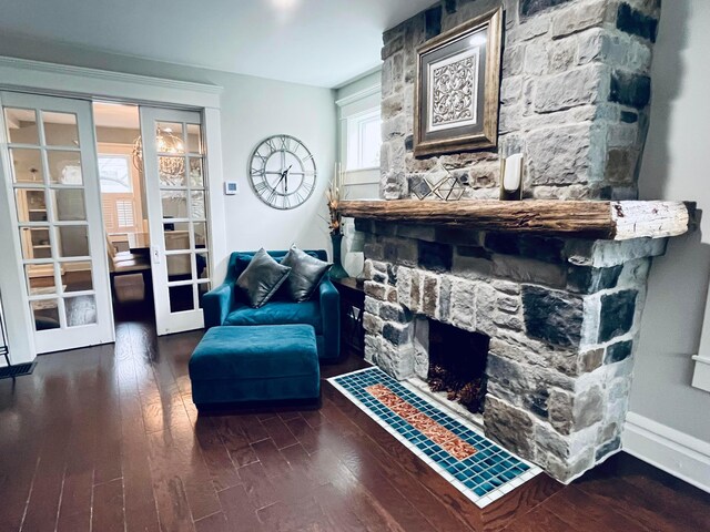 sitting room featuring french doors, baseboards, a stone fireplace, and wood finished floors