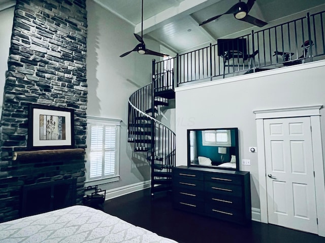 bedroom with baseboards, wood finished floors, beam ceiling, and a towering ceiling