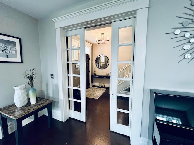 entryway featuring baseboards, a notable chandelier, and dark wood-type flooring
