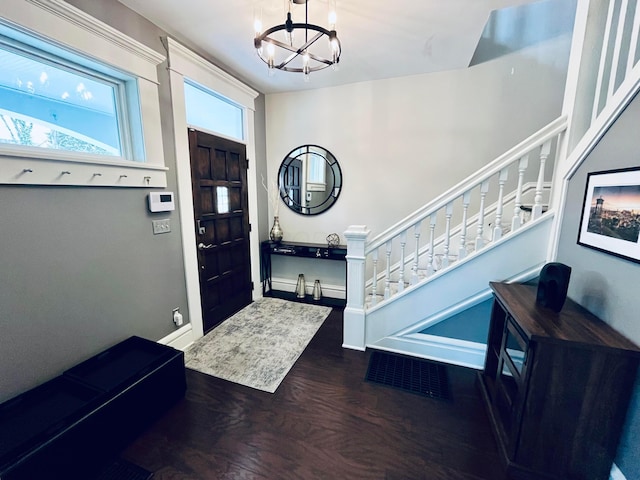 entryway featuring baseboards, stairs, wood finished floors, and a notable chandelier