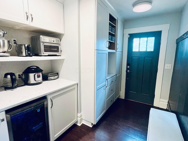 interior space with dark wood-type flooring, baseboards, and wine cooler