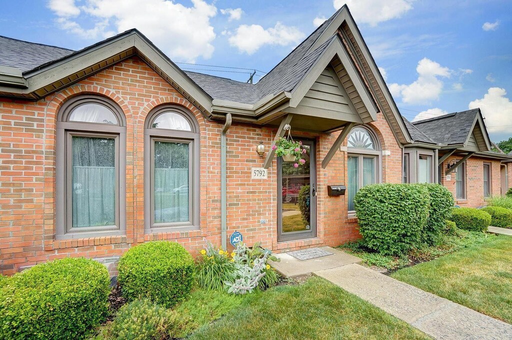 entrance to property with a shingled roof and brick siding