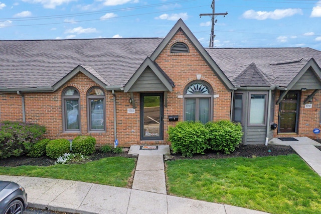 5792 Thada Ln, Columbus, OH 43229 - tudor house featuring a front lawn, brick siding, and roof with shingles