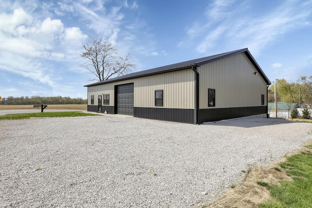 view of outdoor structure with gravel driveway and an outbuilding