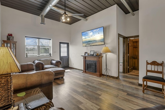 living room featuring a high end fireplace, high vaulted ceiling, beam ceiling, and wood finished floors