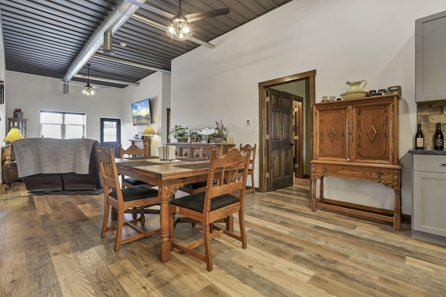 dining area featuring ceiling fan, beam ceiling, and light wood-type flooring