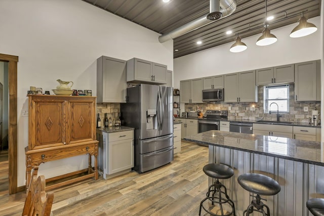 kitchen featuring a breakfast bar area, a sink, stainless steel appliances, and decorative backsplash