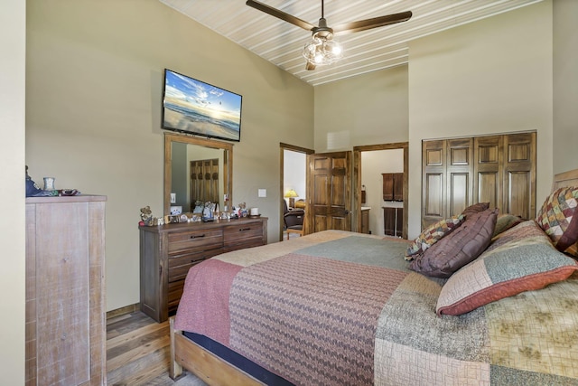 bedroom featuring a high ceiling, a ceiling fan, and wood finished floors