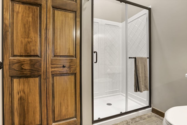 full bathroom with toilet, a stall shower, and baseboards
