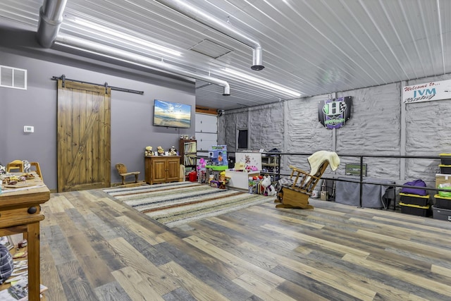 interior space with visible vents, wood finished floors, and a barn door