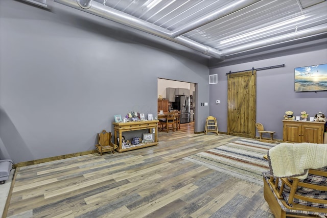 sitting room with wood finished floors, a barn door, and visible vents