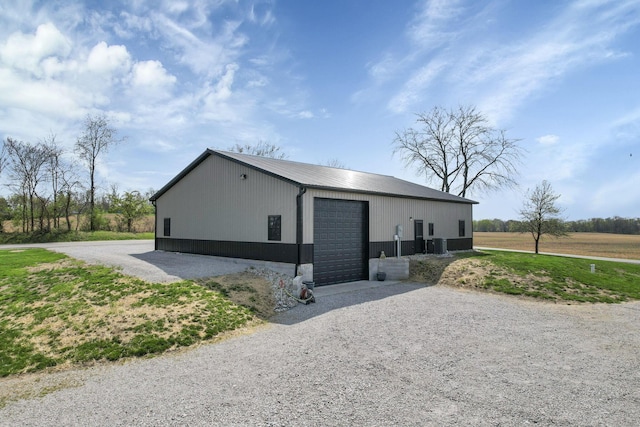 exterior space with metal roof, a detached garage, gravel driveway, and an outbuilding