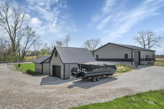 exterior space with metal roof, gravel driveway, an outbuilding, and a garage