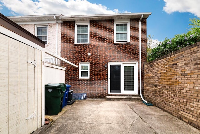 rear view of property with brick siding, fence, and a patio area