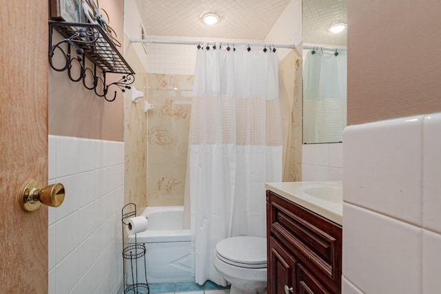 full bathroom with wainscoting, tile walls, toilet, vanity, and shower / tub combo