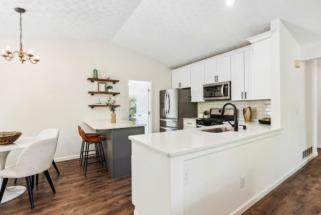 3186 Bowdoin Cir, Columbus, OH 43204 - kitchen featuring stainless steel appliances, a peninsula, dark wood-style flooring, lofted ceiling, and tasteful backsplash