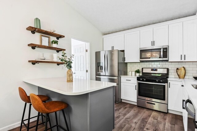 3186 Bowdoin Cir, Columbus, OH 43204 - kitchen featuring stainless steel appliances, tasteful backsplash, a kitchen breakfast bar, vaulted ceiling, and a peninsula