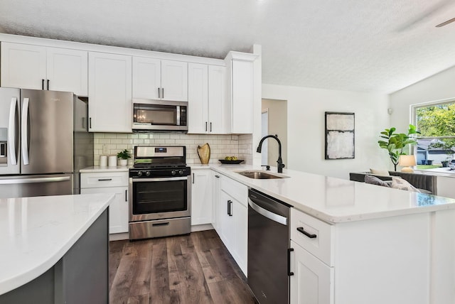 3186 Bowdoin Cir, Columbus, OH 43204 - kitchen with stainless steel appliances, a sink, a peninsula, a textured ceiling, and dark wood finished floors