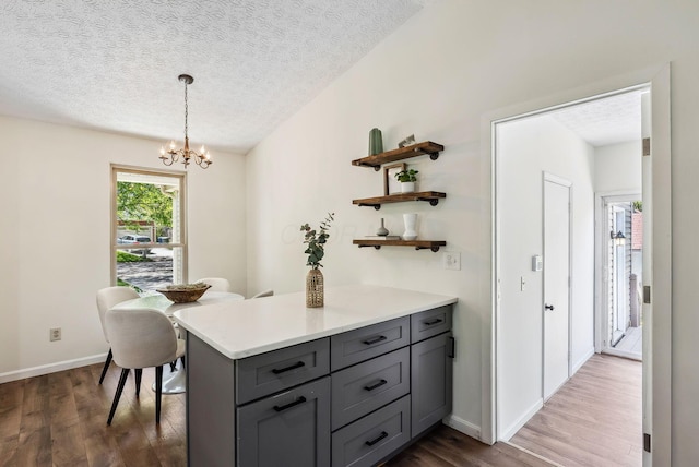 3186 Bowdoin Cir, Columbus, OH 43204 - kitchen with gray cabinets, dark wood-style flooring, a textured ceiling, open shelves, and a chandelier