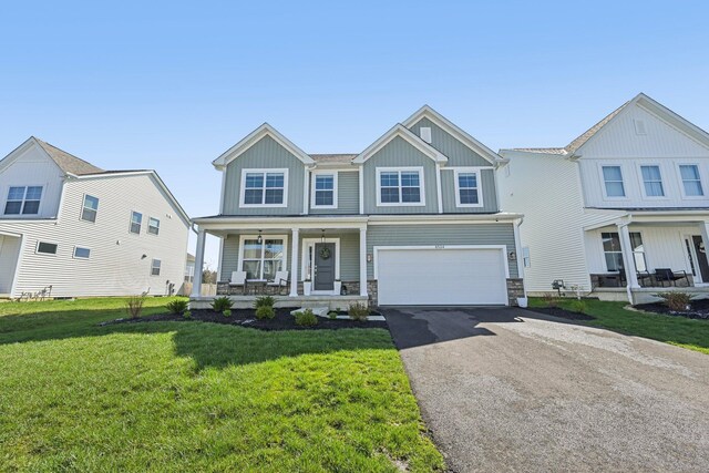 view of front of house featuring a garage, board and batten siding, a front yard, covered porch, and driveway