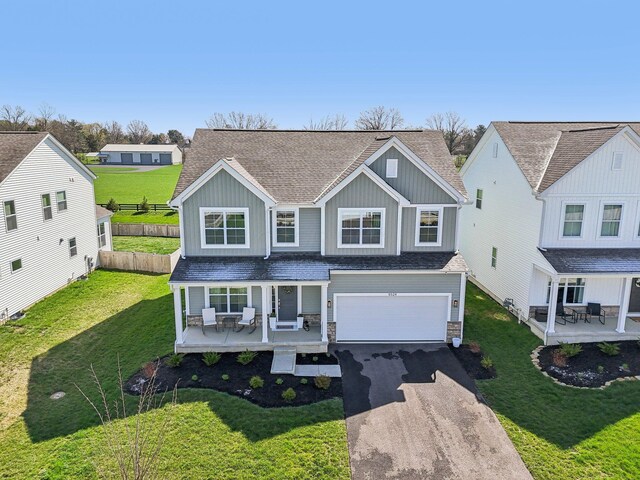 traditional home with fence, an attached garage, aphalt driveway, board and batten siding, and covered porch