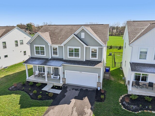 traditional-style home with aphalt driveway, board and batten siding, fence, and covered porch