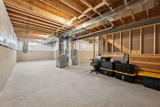 basement with heating unit, electric panel, and electric water heater