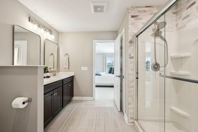 ensuite bathroom with double vanity, a shower stall, a sink, tile patterned floors, and connected bathroom