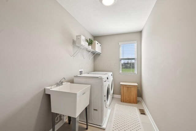 washroom featuring laundry area, independent washer and dryer, visible vents, a sink, and baseboards