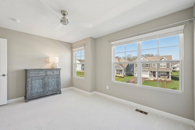 empty room featuring visible vents, baseboards, ceiling fan, and light colored carpet