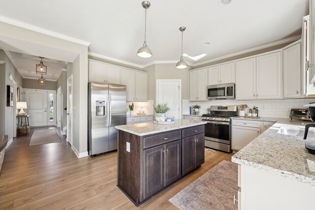 kitchen featuring decorative backsplash, dark brown cabinetry, appliances with stainless steel finishes, a center island, and ornamental molding